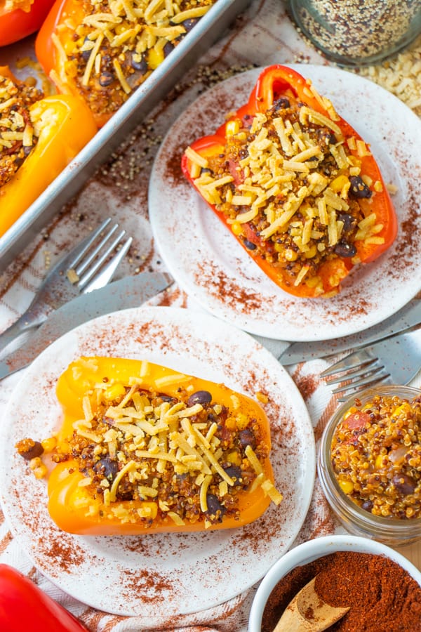 Two stuffed peppers on two white plates.