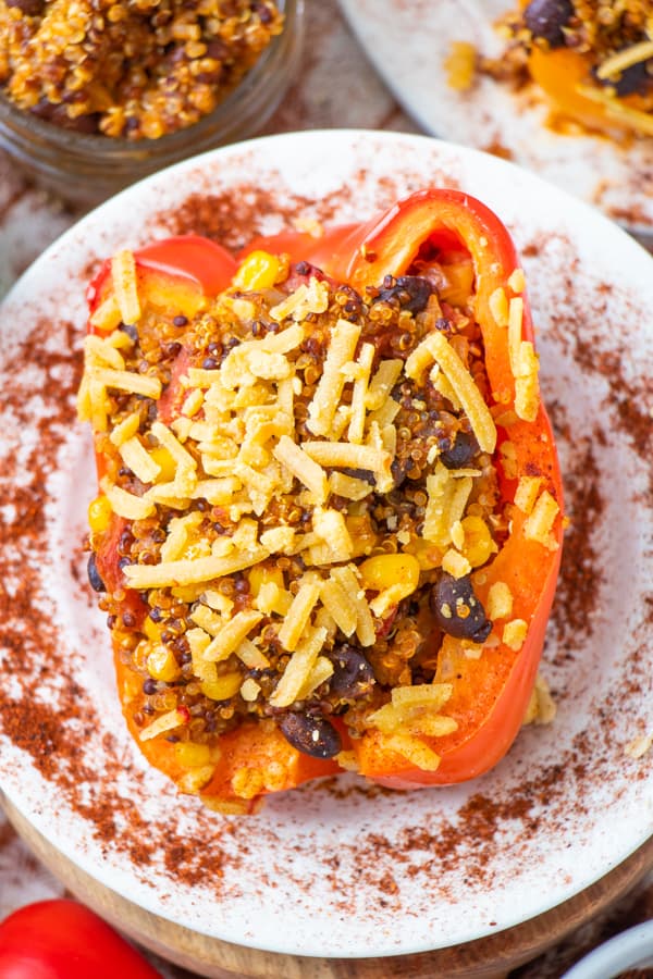 Red stuffed pepper on a white plate with chili powder on it.