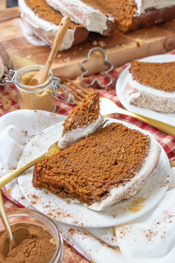 Gingerbread slice on a white plate with spices surrounding.