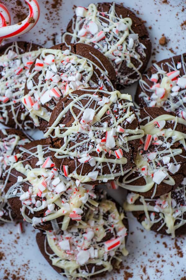 Dark chocolate cookies with white chocolate drizzle and candy cane pieces on top.