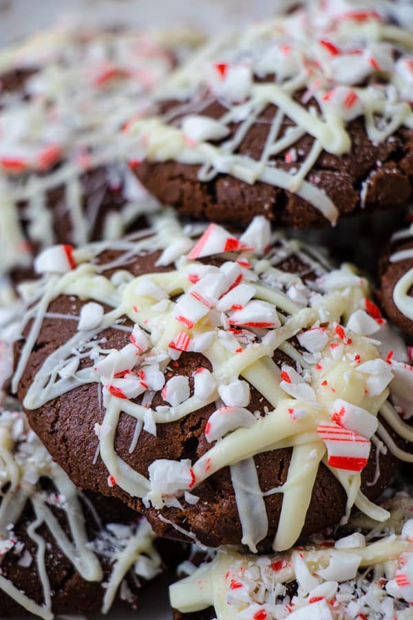 Close up of white chocolate drizzle and candy cane pieces on a chocolate cookie.