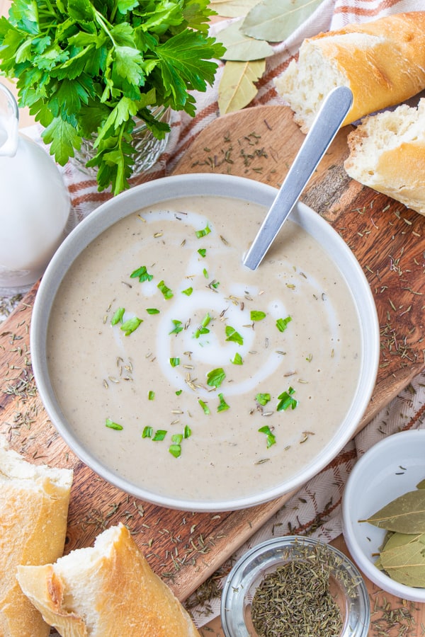 Soup served on a wooden platter with fresh bread around.