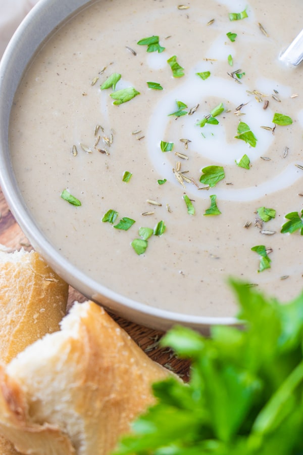 Soup in serving bowl with fresh bread and parsley in the foreground.