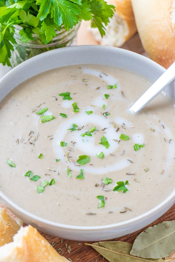 Soup in serving gray bowl with silver spoon and parsley.