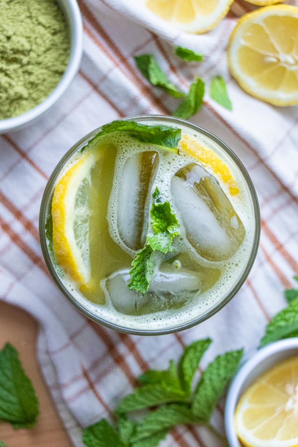 Lemonade with ingredients in bowls around cup.