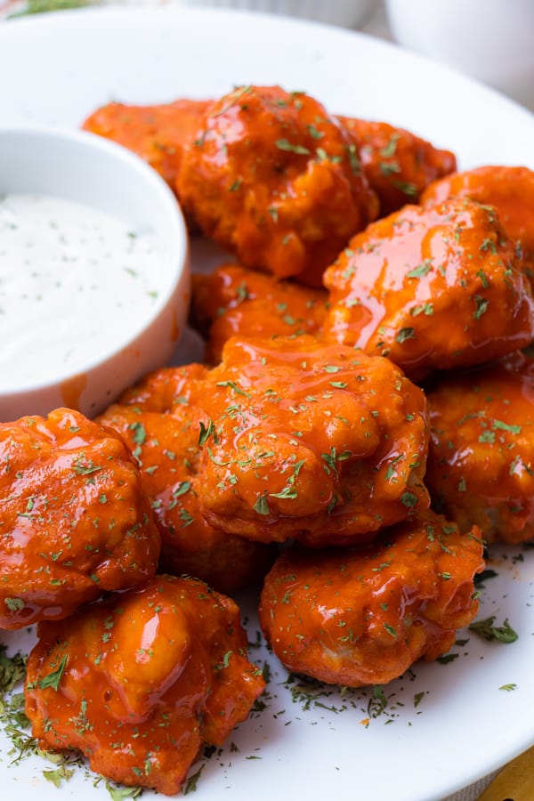 Hot wings with ranch on white plate.