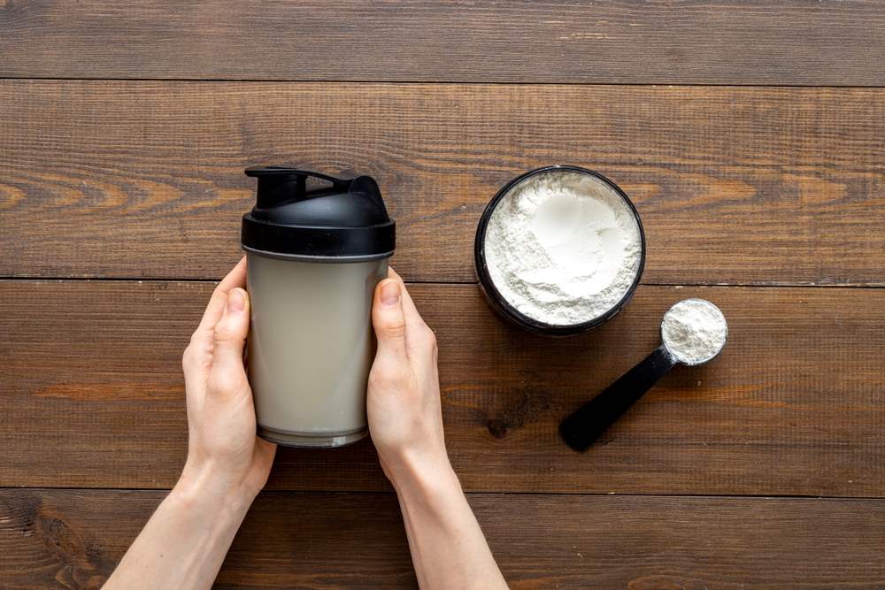 Blender bottle with protein powder on table.
