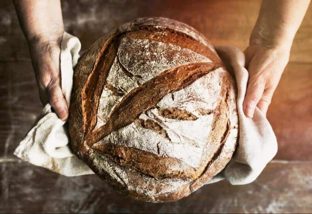 Hands holding a loaf of sourdough bread